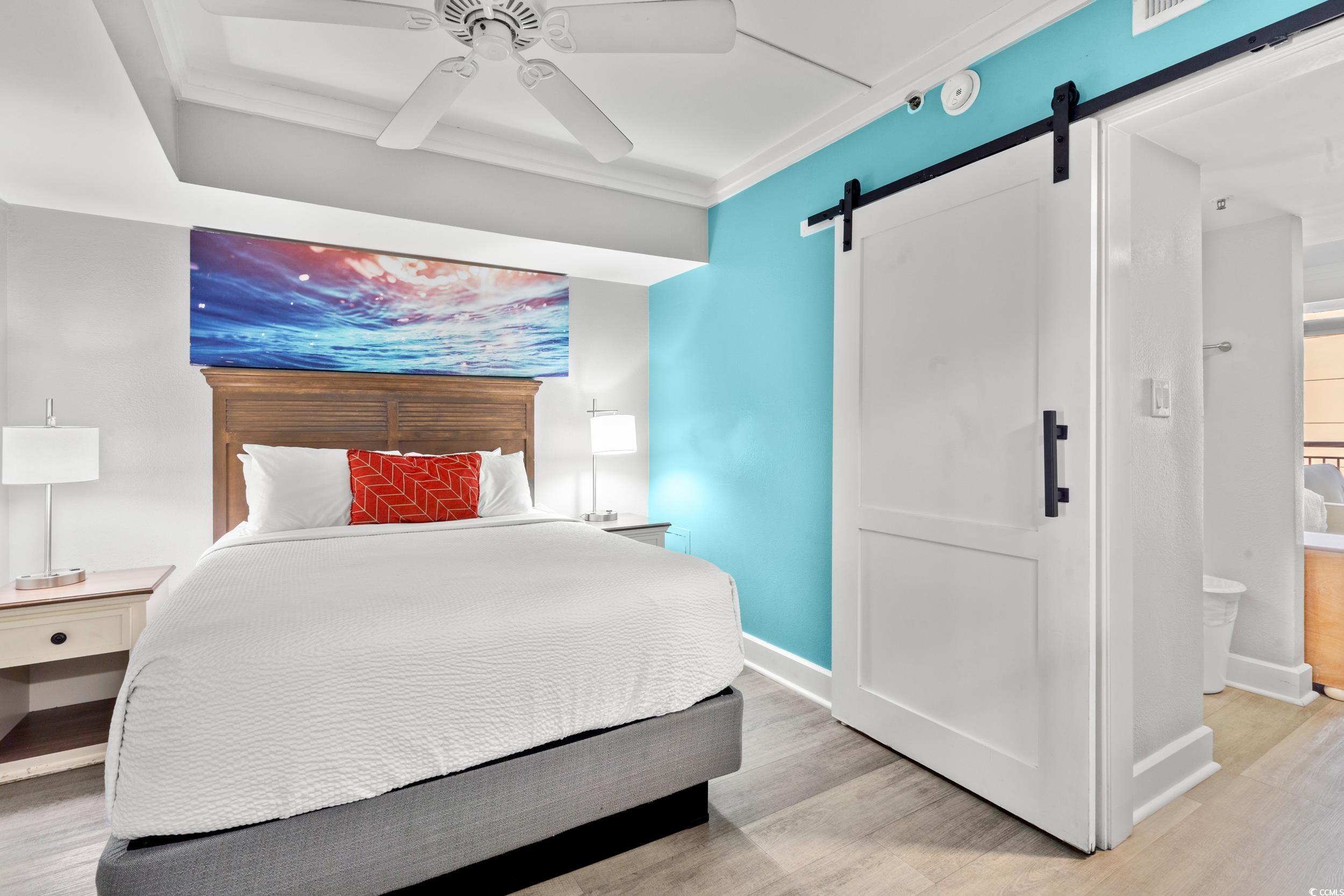 Image 3: Bedroom featuring a barn door, ornamental molding,