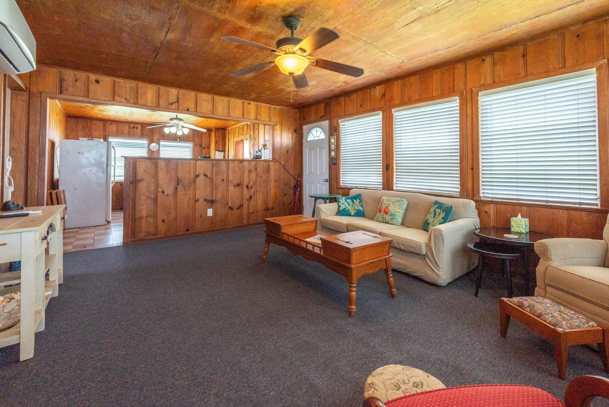 Image 2: Cozy living area with wood paneling, carpeted floo