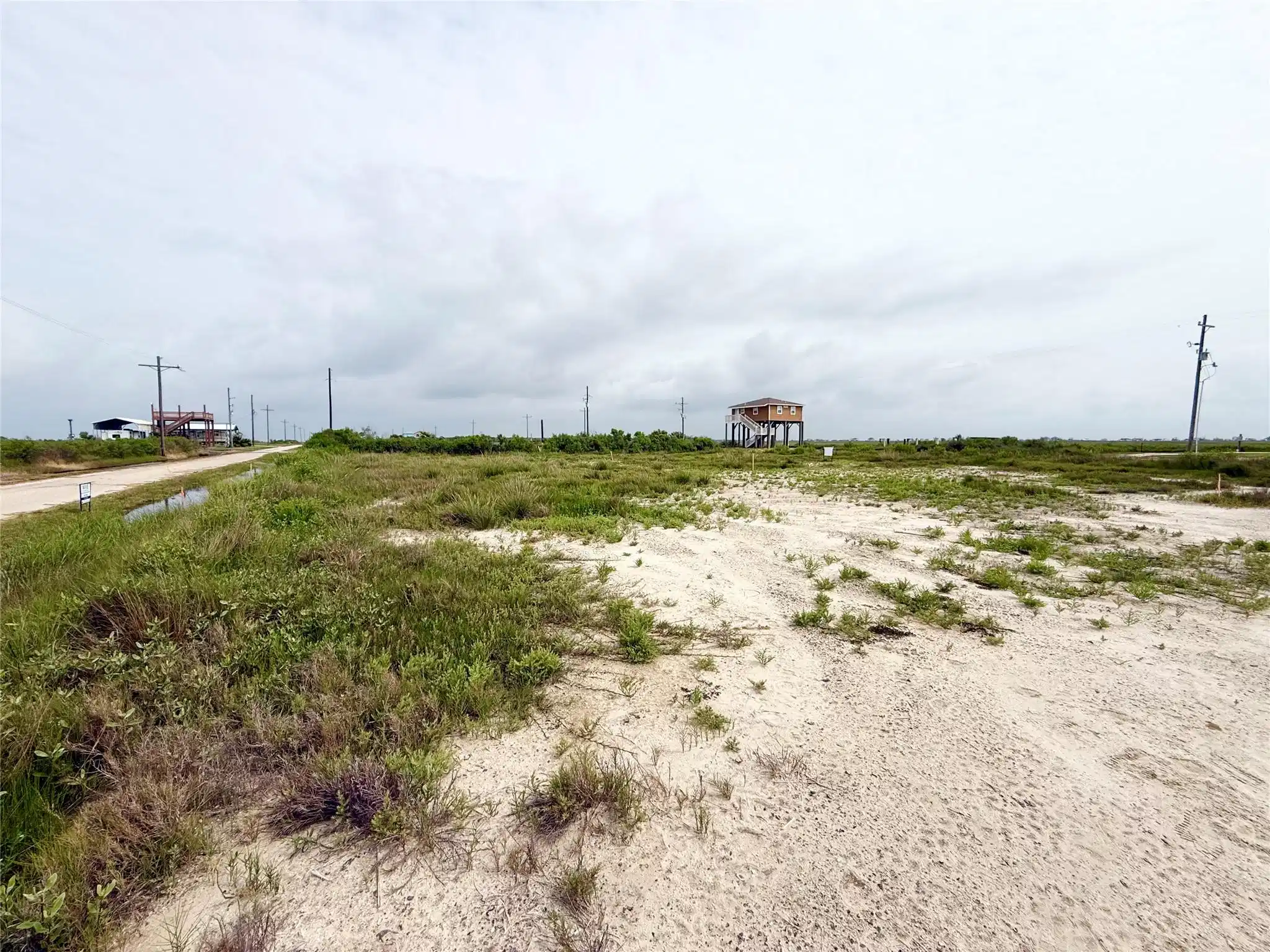 Image 1: Expansive open lot with sandy terrain and lush gre