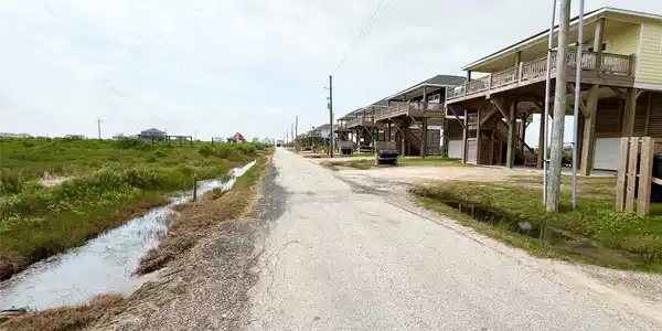 Image 4: Elevated coastal homes line a quiet rural road, of