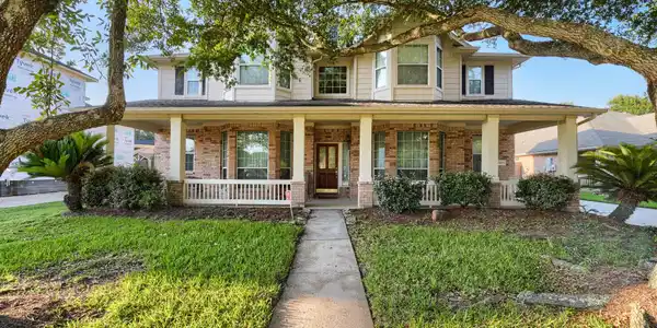 Image 2: Mature trees grace the property with a covered fro