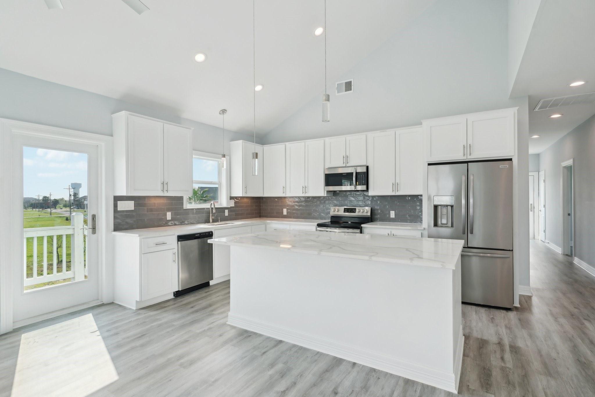 Image 3: Modern kitchen featuring white cabinetry, a large
