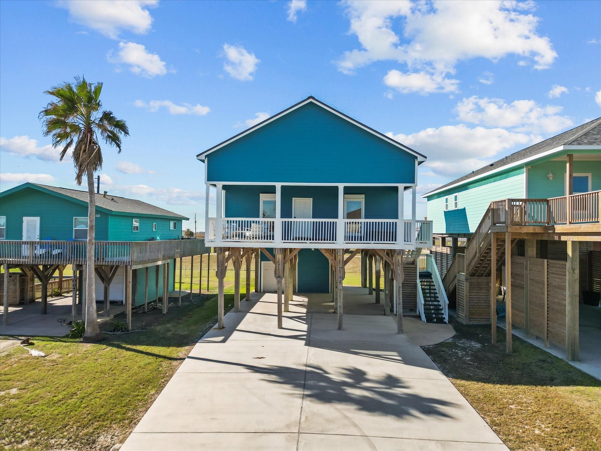 Image 3: This elevated beach house features a vibrant blue