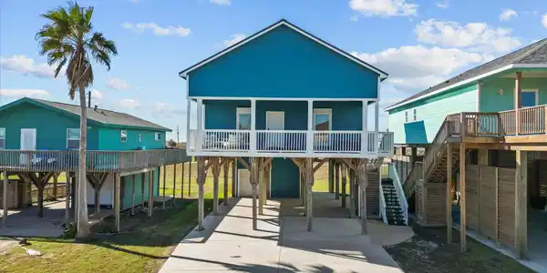 Image 3: This elevated beach house features a vibrant blue