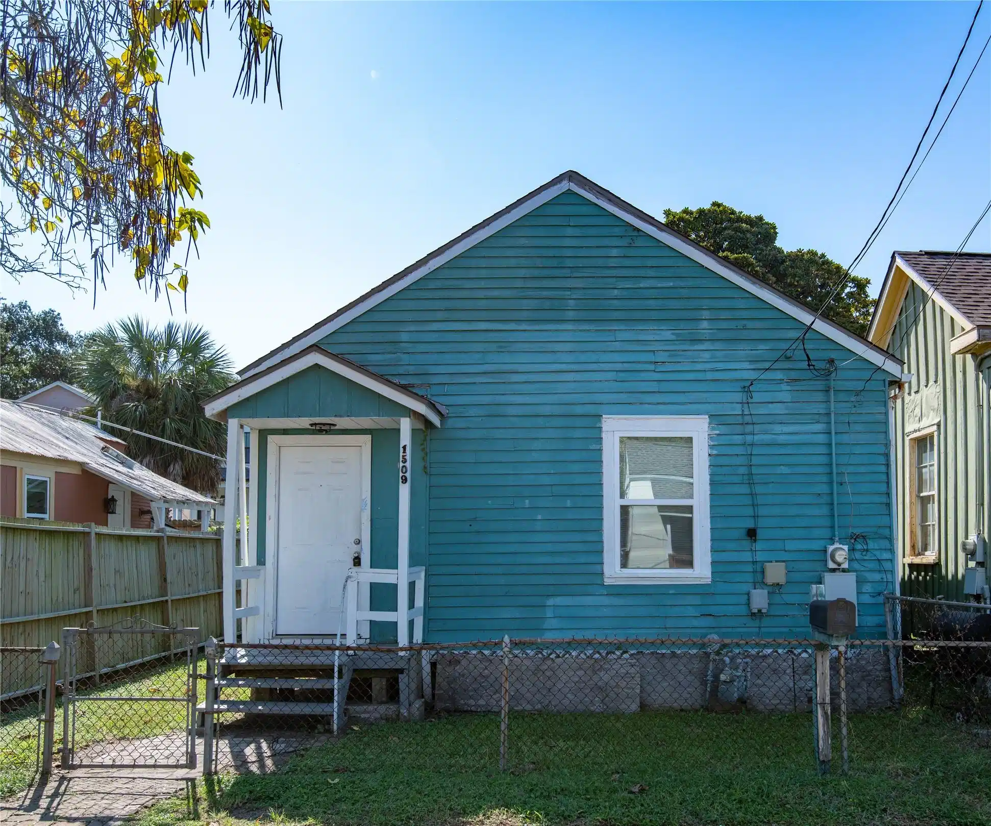 Image 1: This cheerful teal bungalow welcomes you with a fe