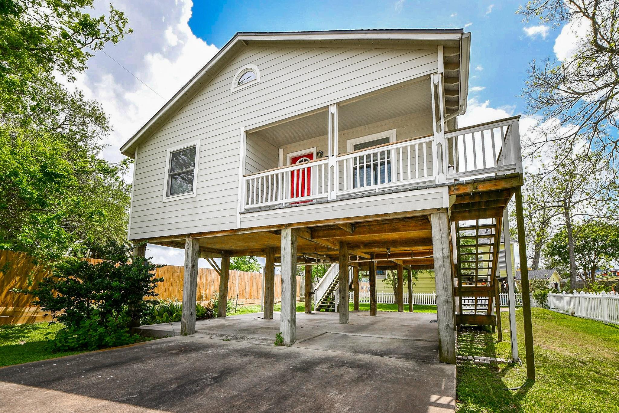 Image 1: Elevated home with a charming front porch and red