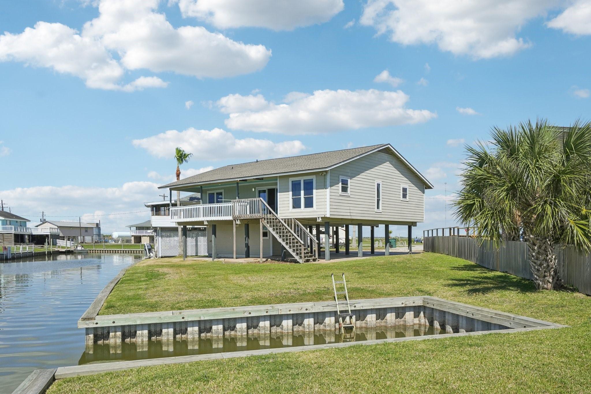 Image 1: This waterfront home features a spacious deck over