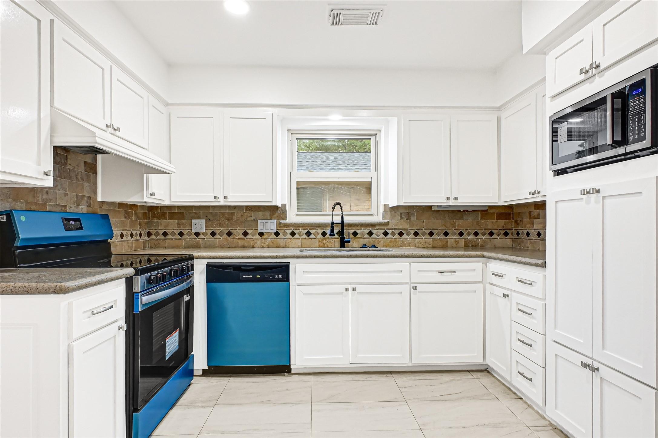 Image 2: This kitchen features modern white cabinetry, a sl
