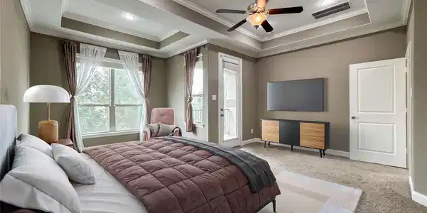 Image 2: The primary bedroom features a tray ceiling with r