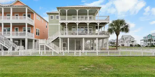 Image 3: Rear exterior with double wraparound porches, fenc