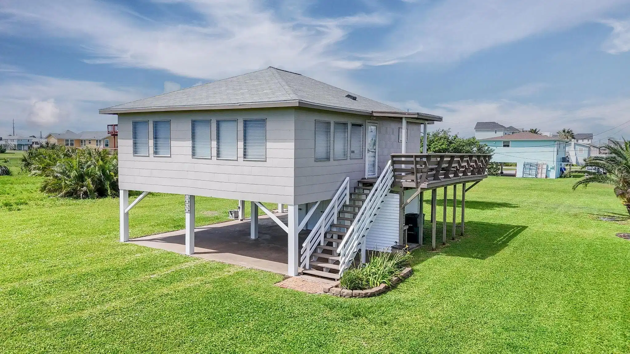 Image 1: Elevated coastal home with a partial wraparound de