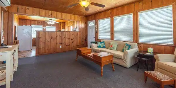 Image 2: Cozy living area with wood paneling, carpeted floo
