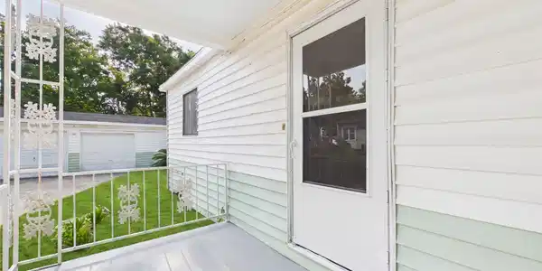 Image 4: Charming, covered porch with decorative railing of