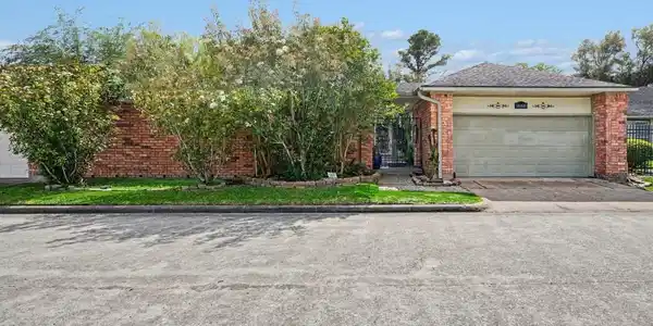 Image 2: Charming curb appeal with lush landscaping and a r