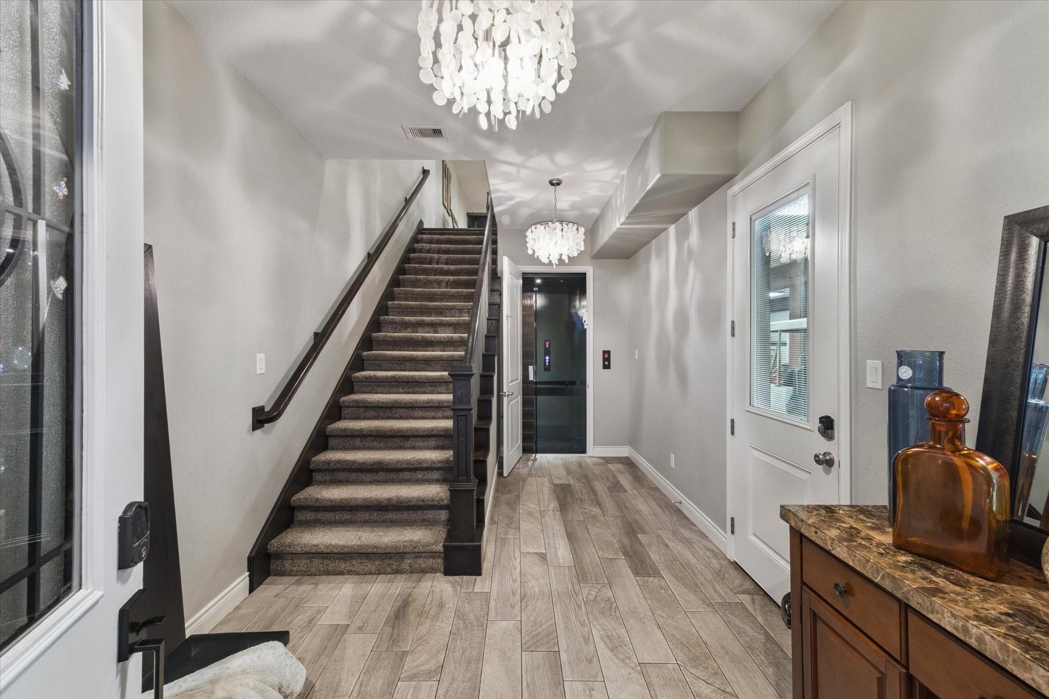 Image 4: Bright entry with wood-look floors, chandelier, an