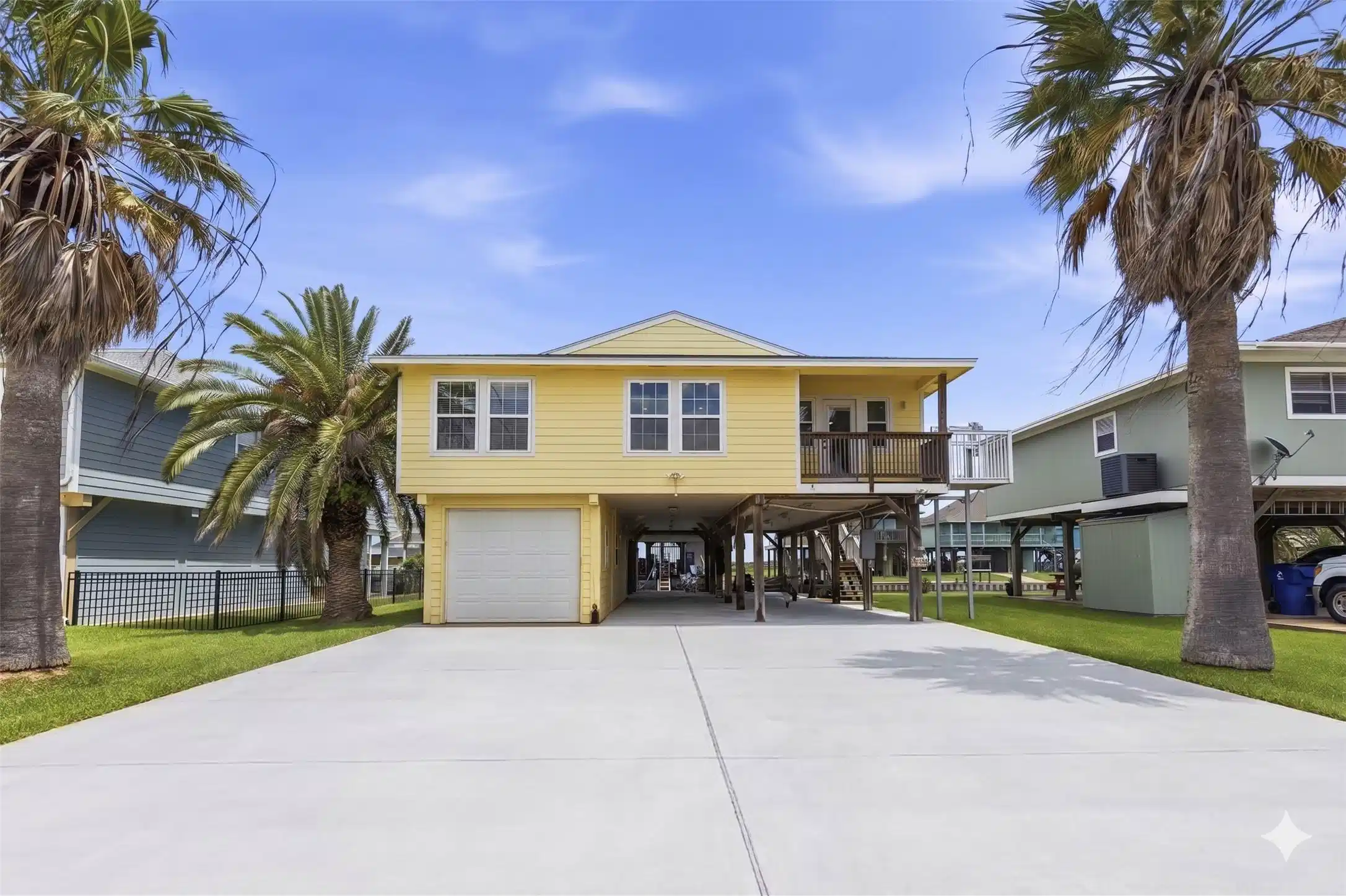 Image 1: Front exterior &mdash; elevated yellow coastal home fram