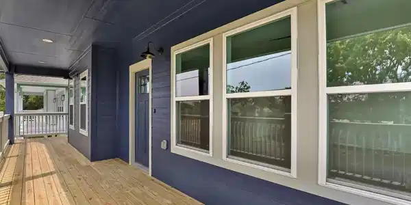 Image 3: Charming covered porch with rich blue siding and a