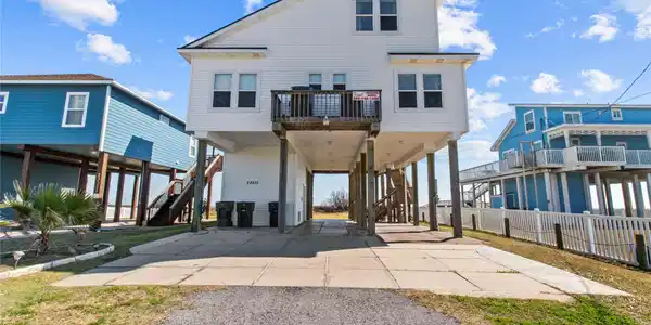 Image 4: Elevated beach house with a white exterior, featur