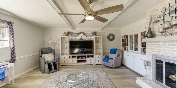 Image 4: The den features a modern ceiling fan, built-in bo