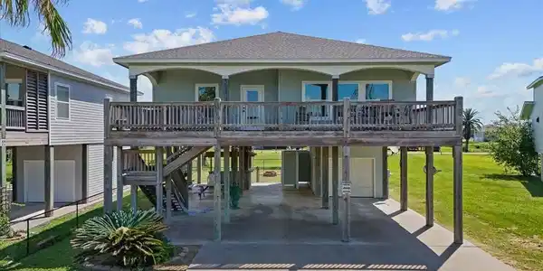 Image 2: This elevated home features an expansive deck, ide