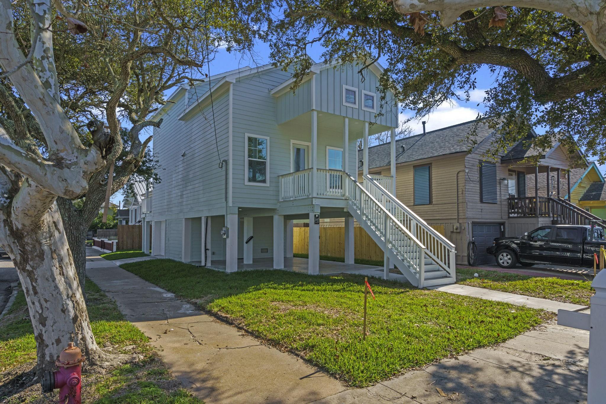 Image 4: This elevated, light green home features a charmin