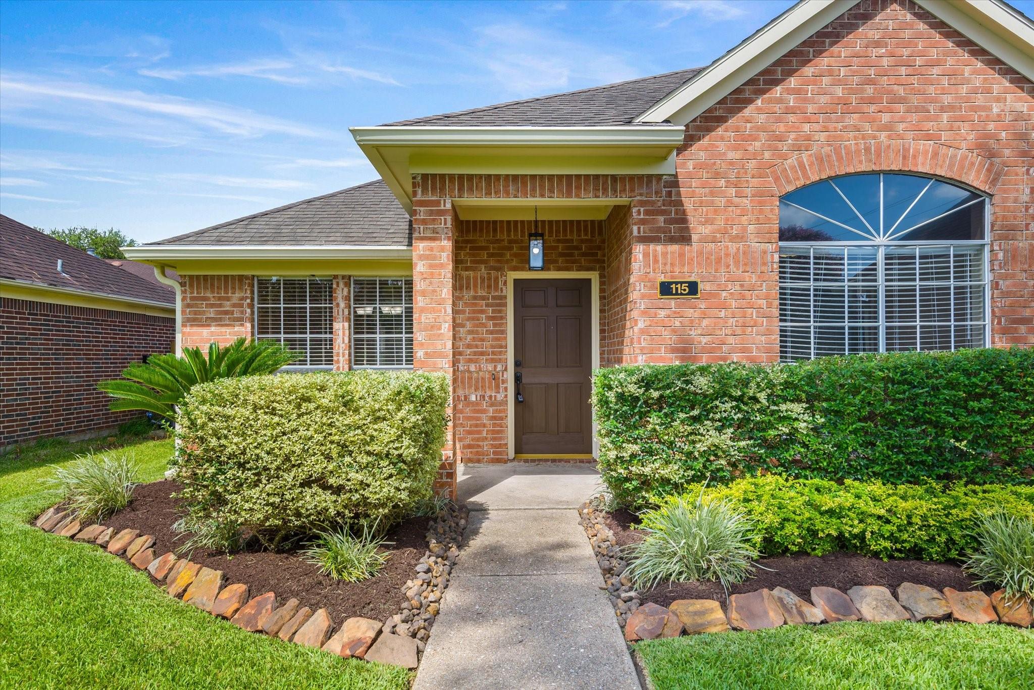 Image 4: Covered front entry with lush landscaping.