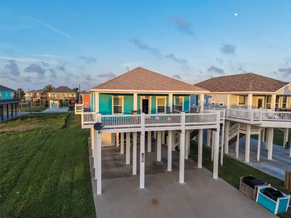 Image 1: Elevated beach home sits on stilts with expansive