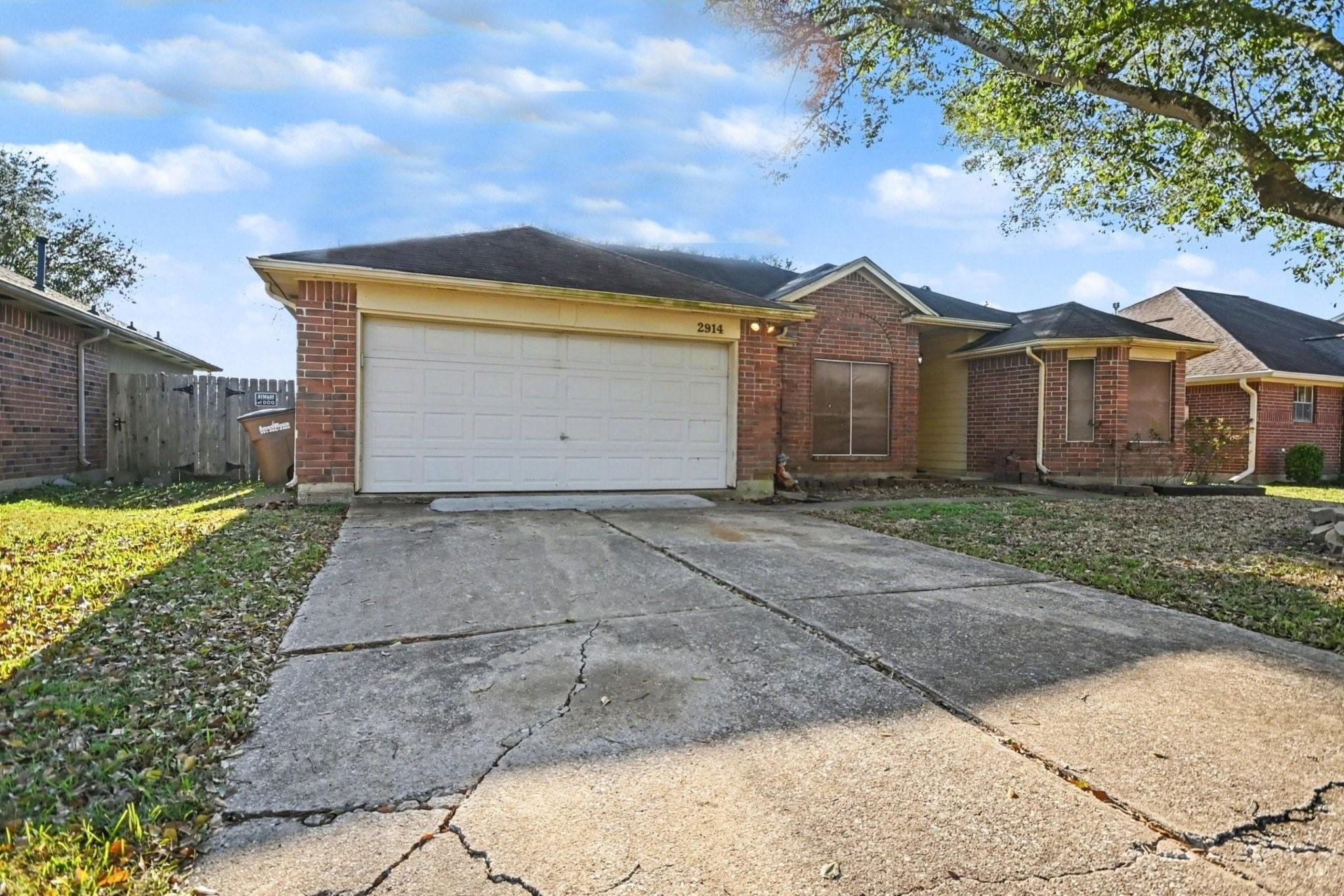 Image 2: Brick home with a two-car garage, a sloped roof, a