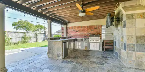 Image 3: Outdoor kitchen and tile flooring and a TV