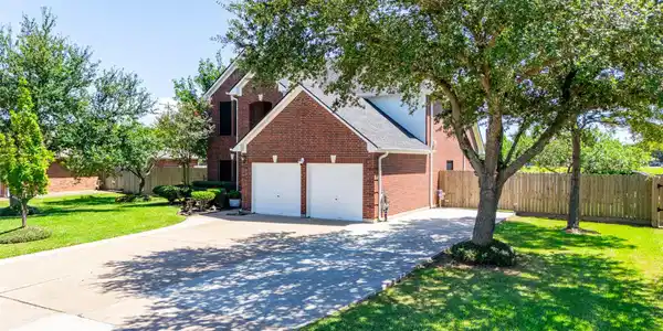 Image 2: Beautiful two-story brick exterior framed by matur