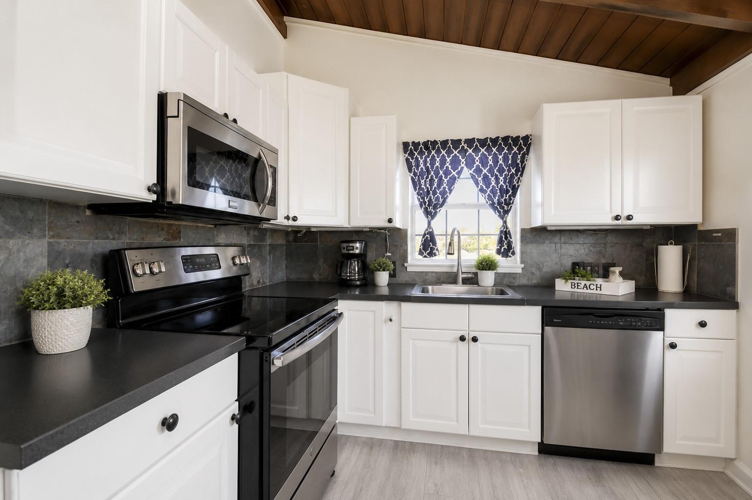 Image 4: Updated kitchen with white cabinetry, stainless ap
