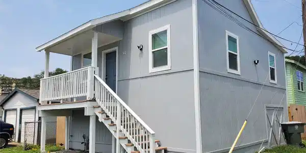 Image 2: This is a raised, gray, two-story home with a cove