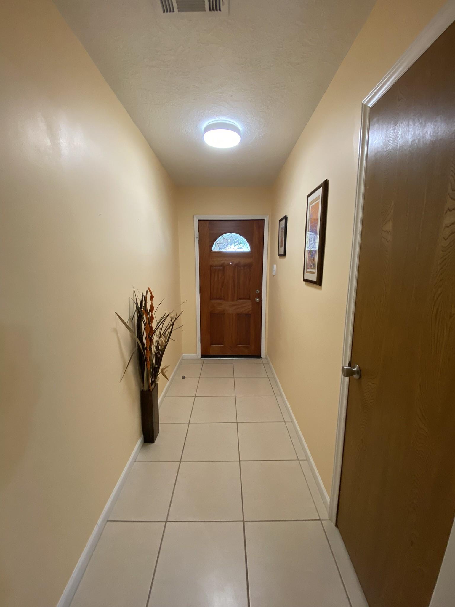 Image 4: This hallway features light-colored walls and tile