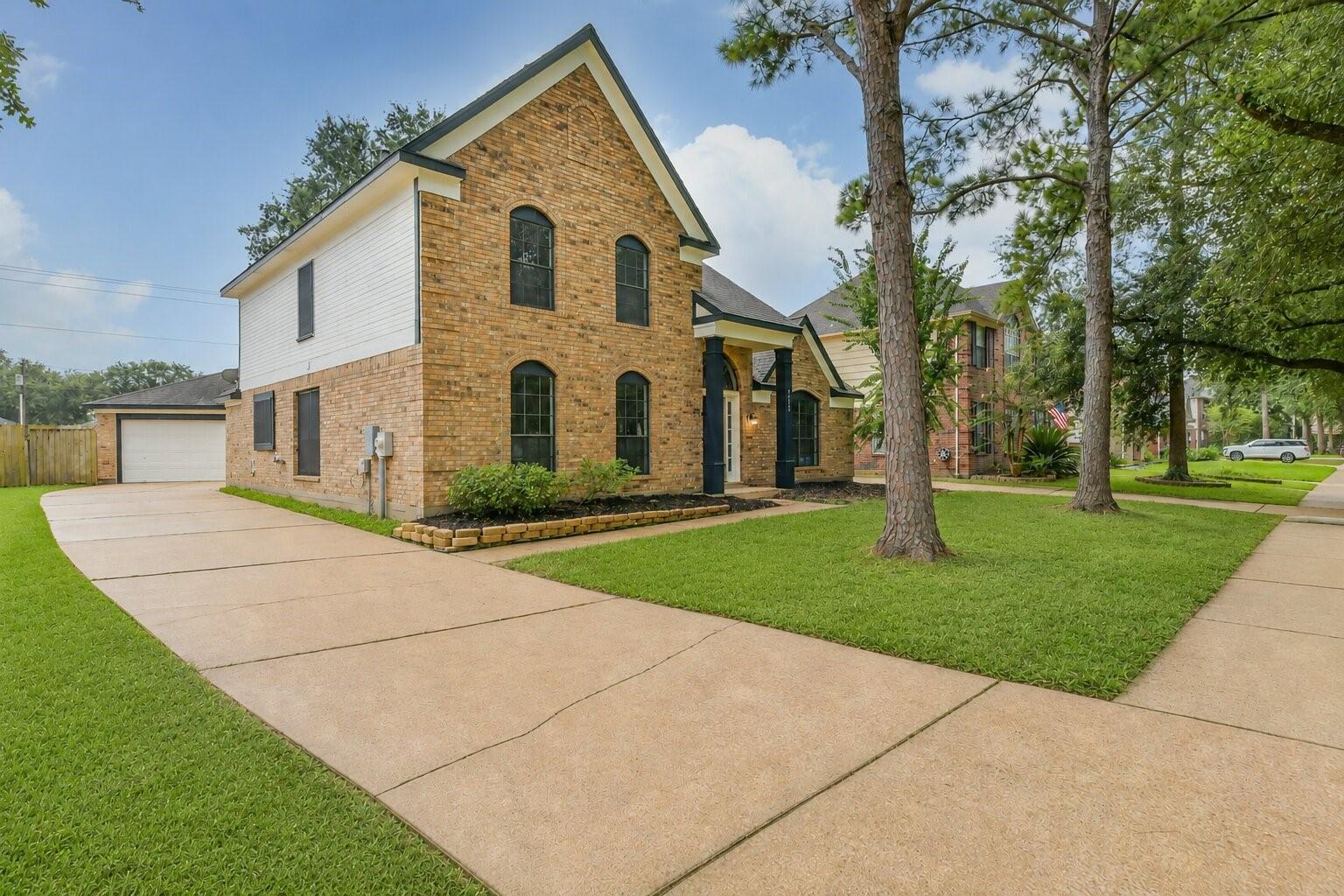Image 2: Two-story brick house with a well-maintained lawn