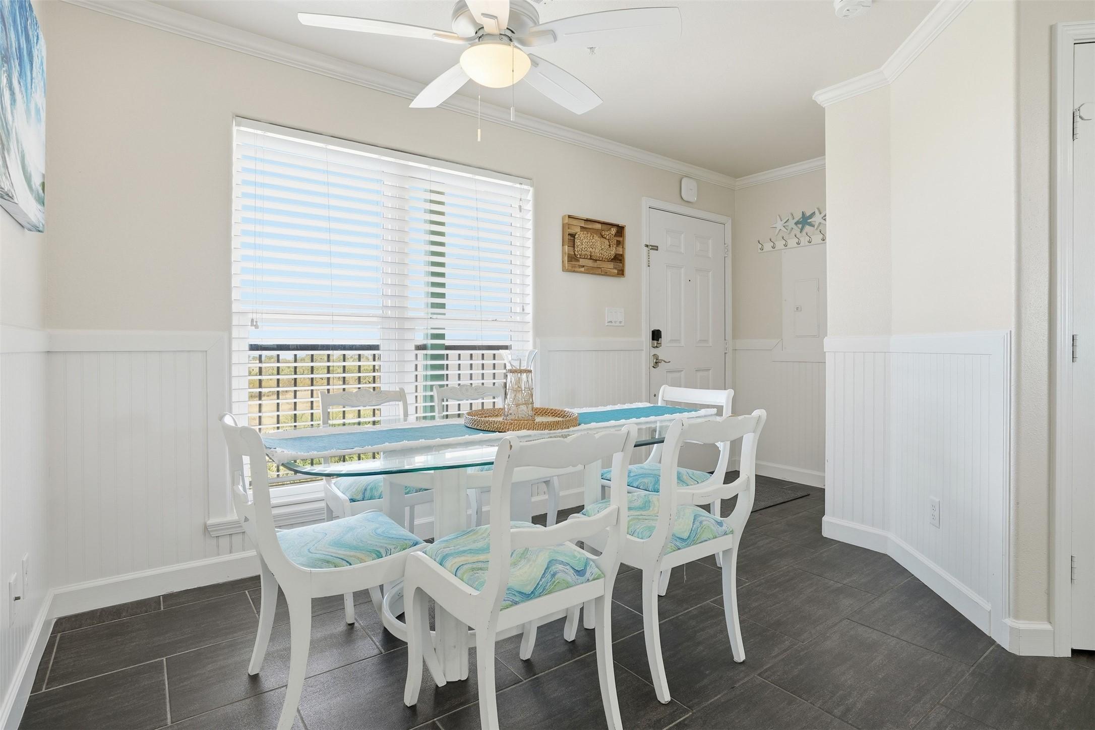Image 3: Bright dining area with a coastal theme. The room
