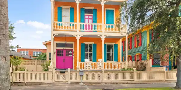 Image 2: This vibrant two-story home features a bold orange
