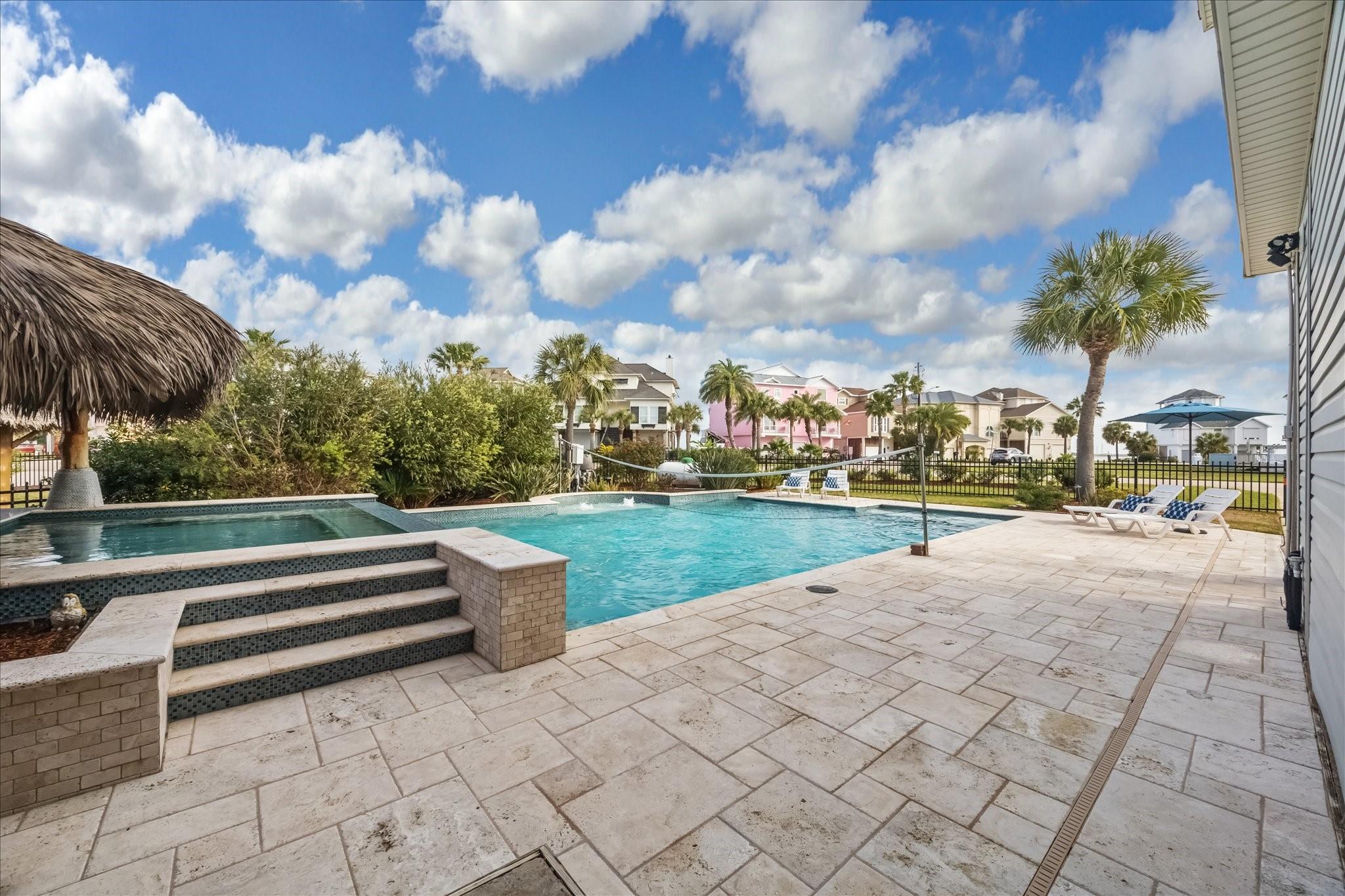 Image 4: Luxurious pool, a stone-tiled deck, and a palapa.