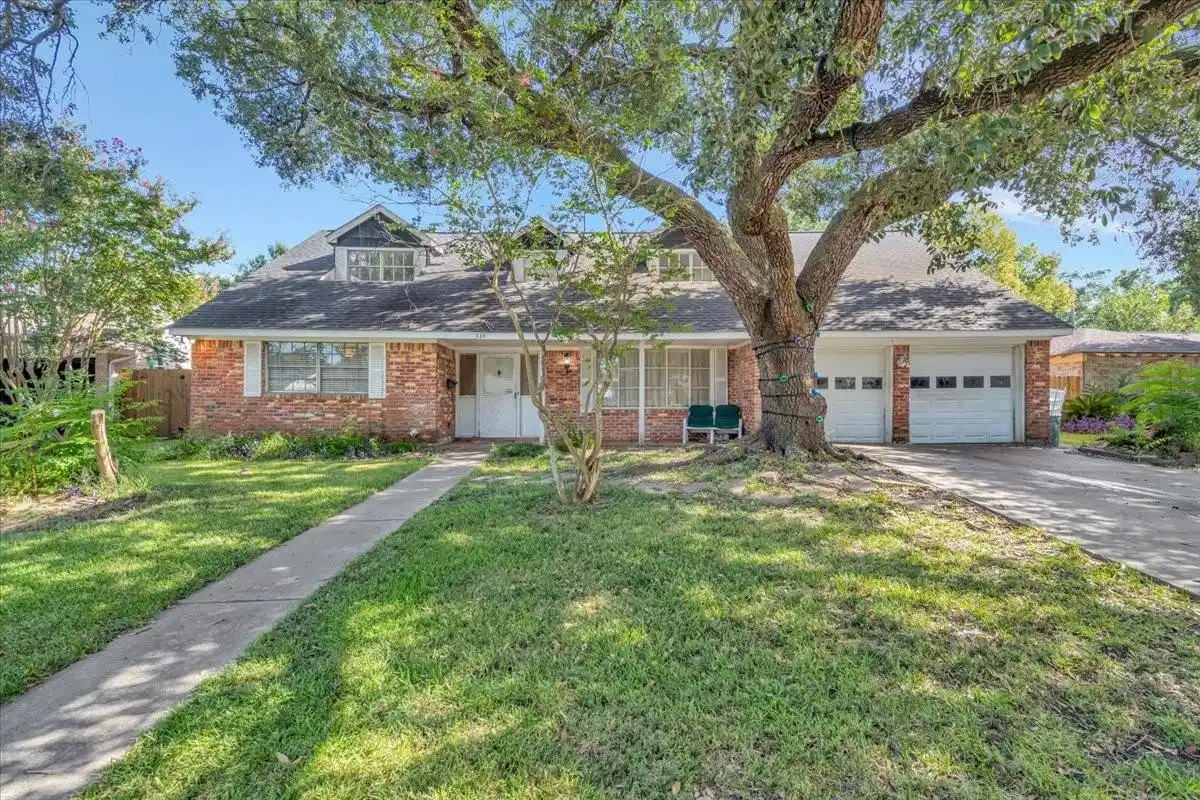 Image 1: Classic brick exterior framed by mature trees, a c