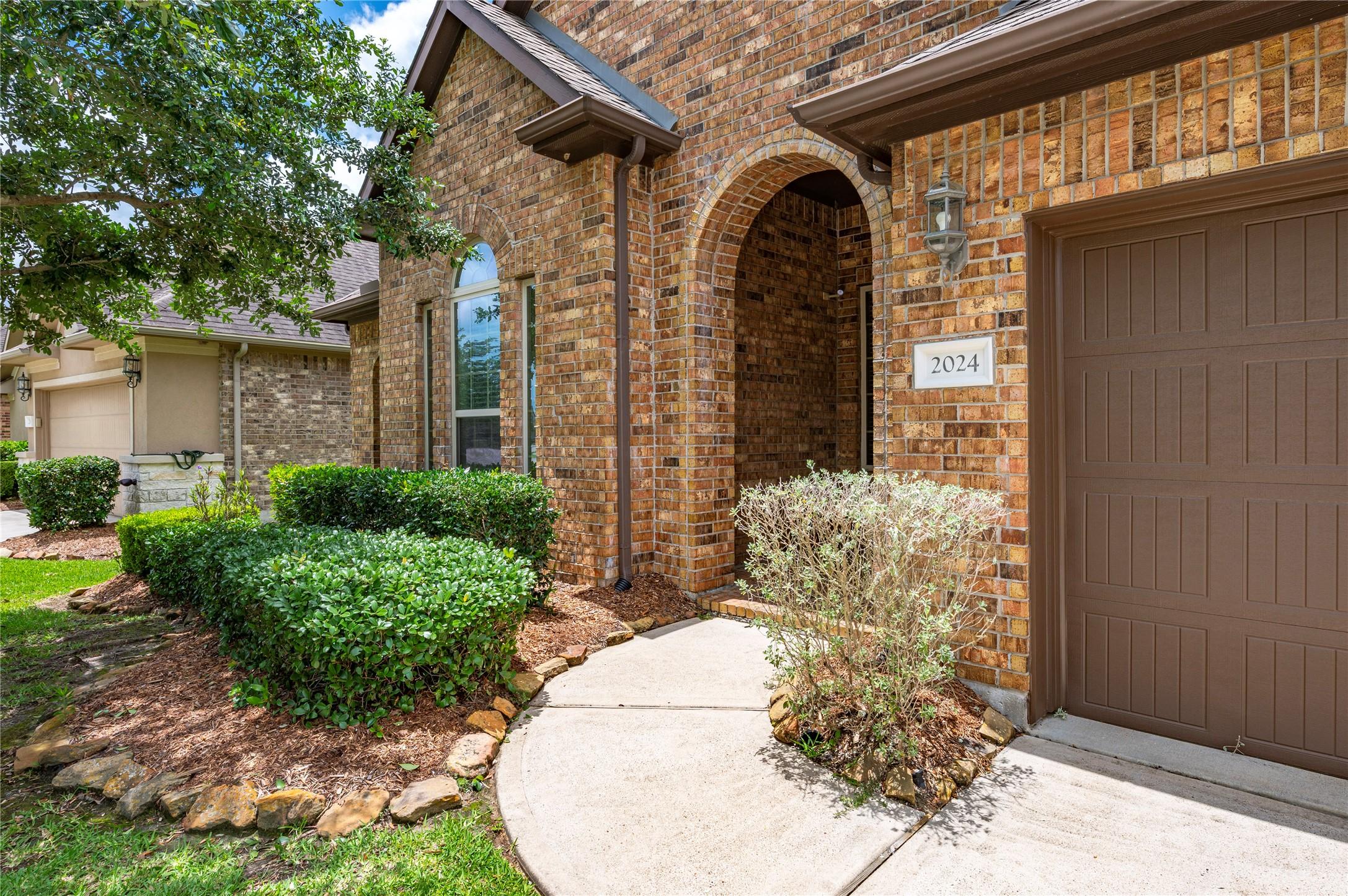 Image 3: Professional landscaping lines the walkway leading