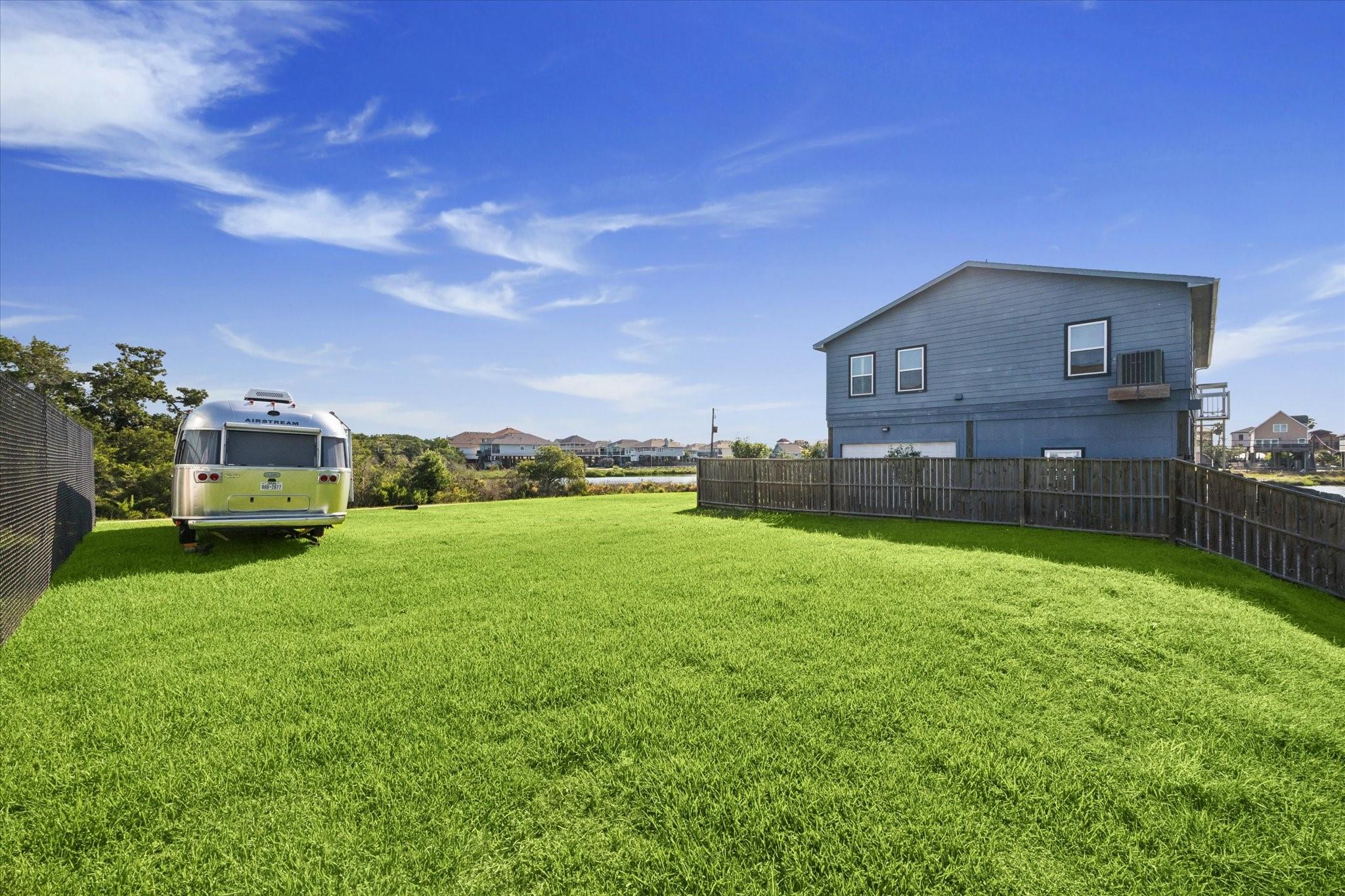 Image 2: Spacious backyard with lush green trees and water