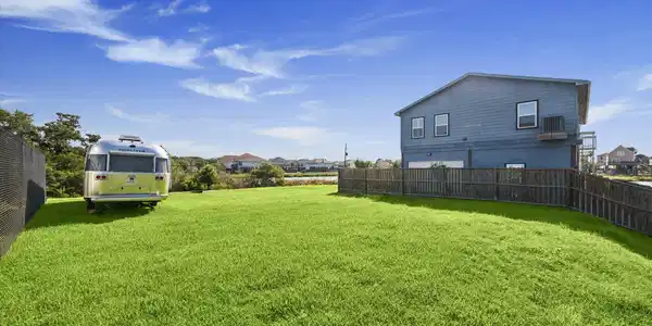 Image 2: Spacious backyard with lush green trees and water