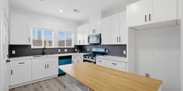Image 4: Bright kitchen with white cabinetry, herringbone b