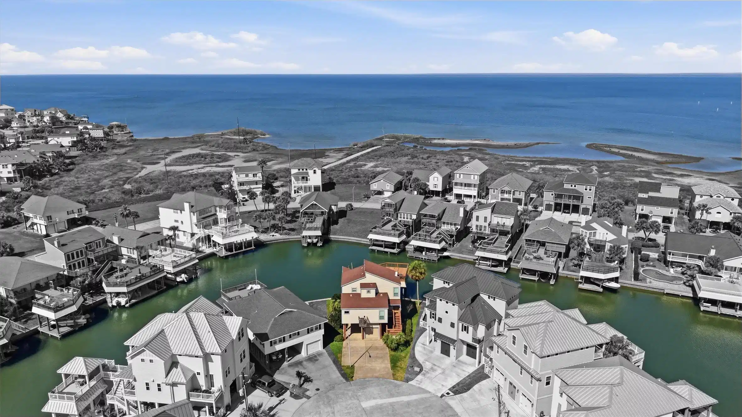 Image 1: Aerial view of a canal-front home with direct bay