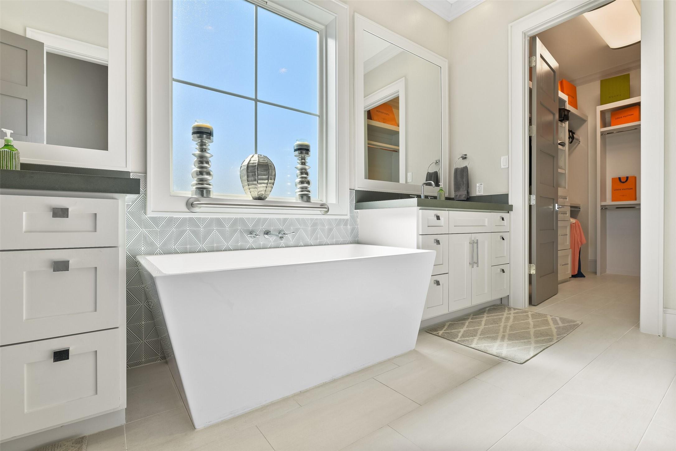 Image 2: The primary bathroom boasts designer tile and a sl