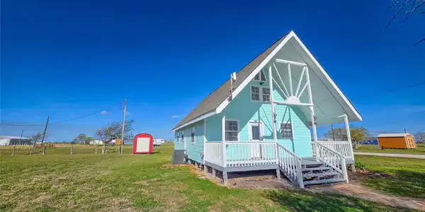 Image 2: Charming light blue A-frame house with white trim,