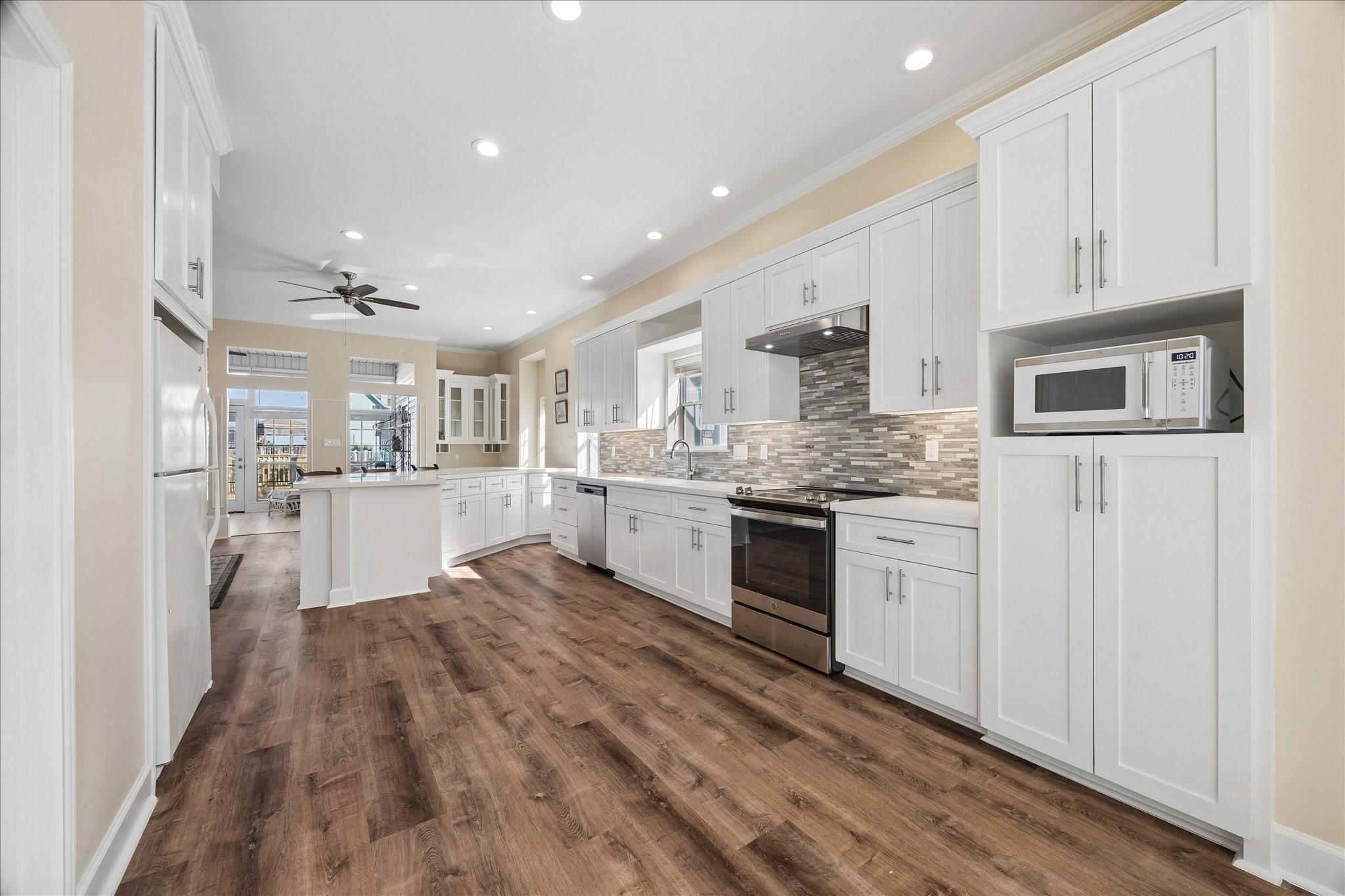 Image 3: This spacious kitchen features modern white cabine