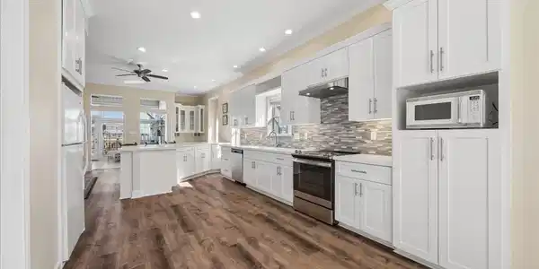 Image 3: This spacious kitchen features modern white cabine