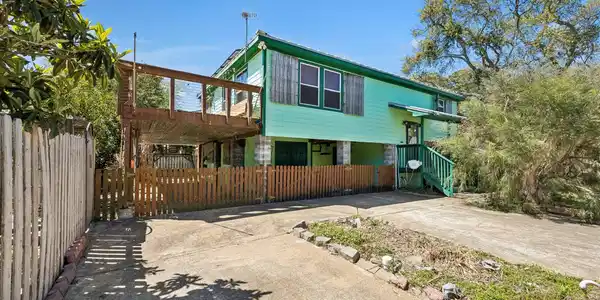 Image 2: Elevated home with a spacious driveway and covered