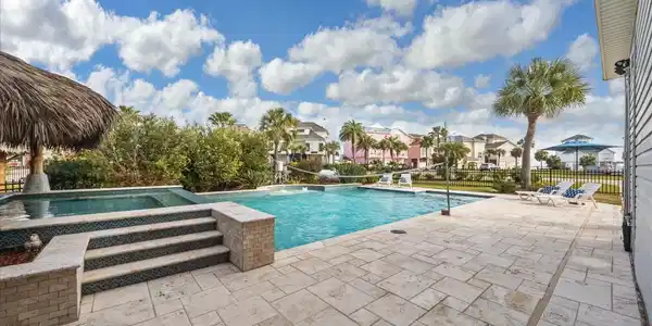 Image 4: Luxurious pool, a stone-tiled deck, and a palapa.