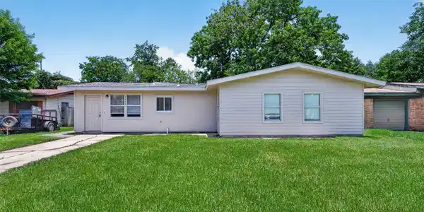 Image 2: Charming single-story home with light siding and a